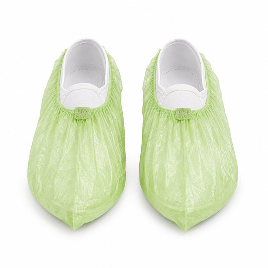 Pair of green PLA/PBAT shoe covers on white background