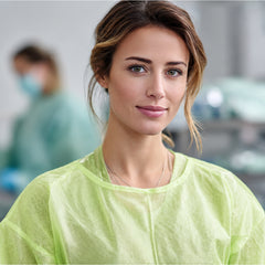 Close-up of person wearing green isolation gown in a work area