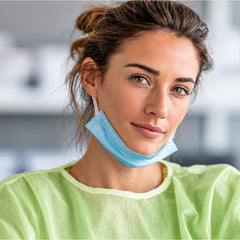 Person wearing green disposable gown with face covering lowered