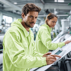 Worker in green protective coverall reviewing production process