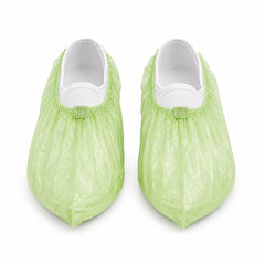 Pair of green PLA/PBAT shoe covers on white background